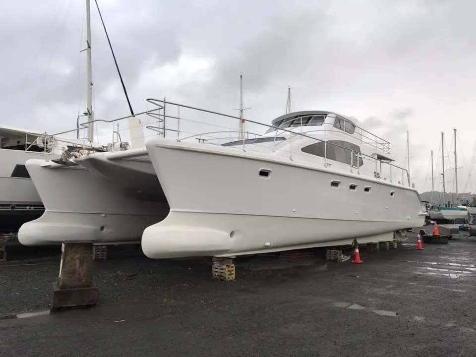 Catamaran standing on supports in a boatyard.