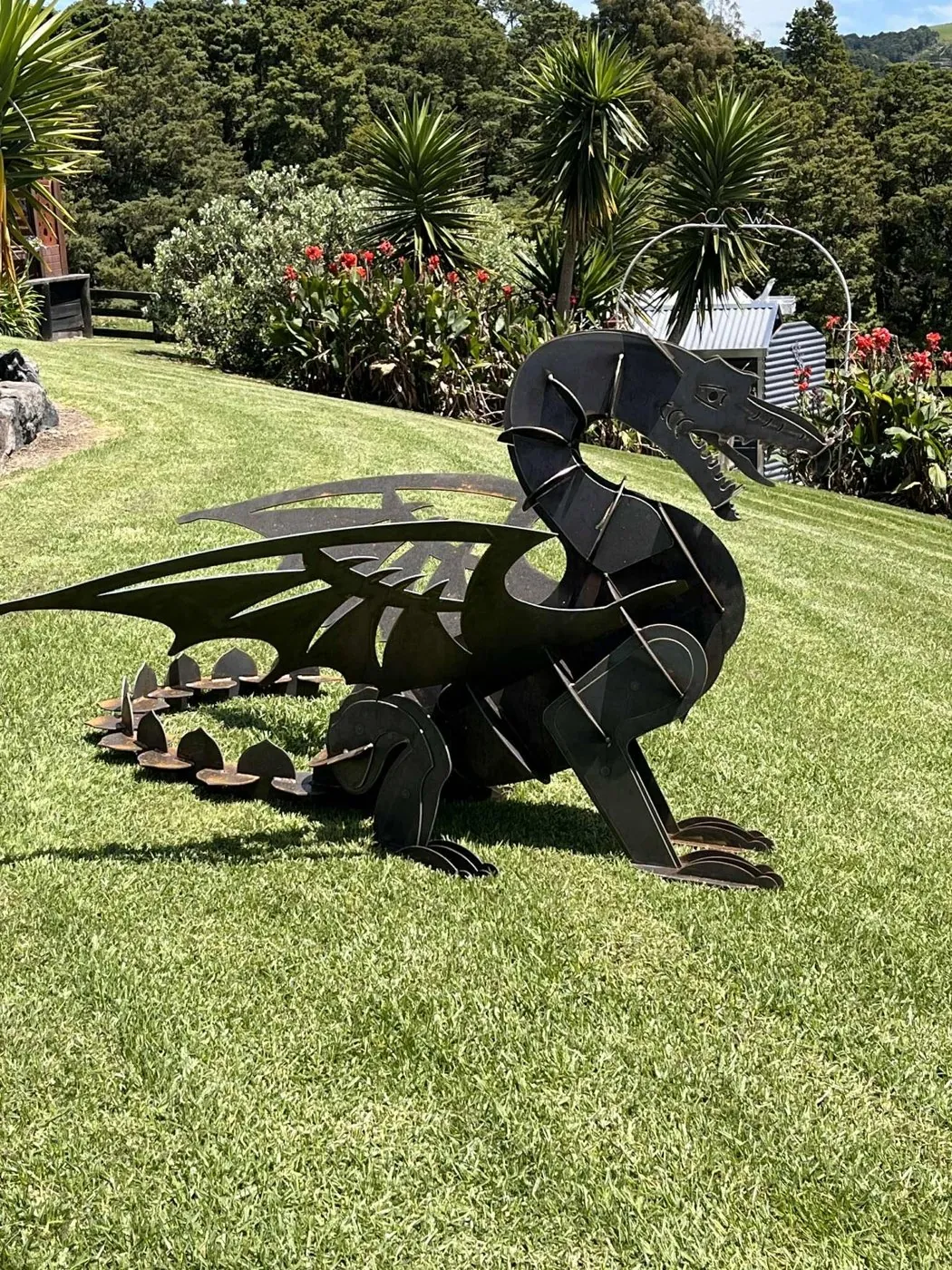 Metal scorpion sculpture on a garden lawn.