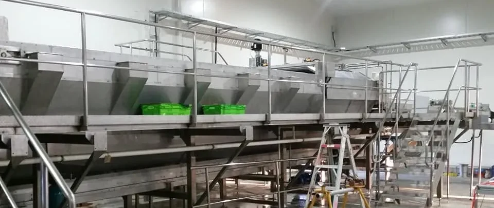 Stairs, tubular handrails and a raised access platform beside stainless steel industrial equipment.