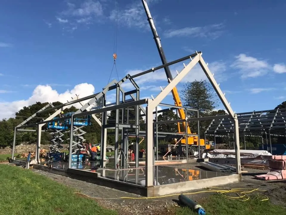 Steel building frame being erected with a crane.